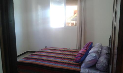 a bedroom with a bed with pillows and a window at Mirleft Trip in Mirleft
