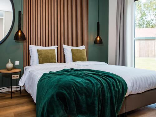 a bedroom with a large bed with a green blanket on it at Calming Hideaway in Veluwe in Voorthuizen