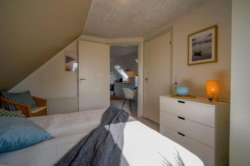 a bedroom with a bed and a dresser with a lamp at FeWo Sjælland B in Sindal