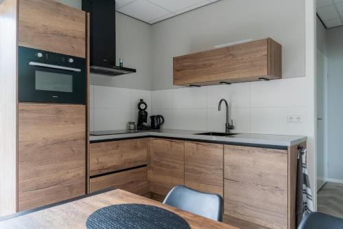 a kitchen with wooden cabinets and a sink and a table at vakantiewoning aan zee en havens 24 in Yerseke