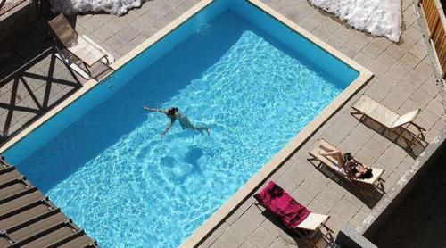 une personne nageant dans une grande piscine bleue dans l'établissement Appt dans chalet résidence Les Balcons du Soleil, à Allos