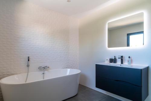 Clohars-CarnoëtにあるVilla des îles - A 350m de la plageの浴槽と鏡のある白いバスルーム