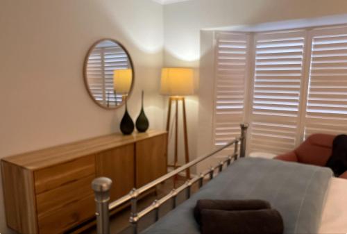 a bedroom with a mirror and a bed and a chair at Cerca Del Agua family and pet friendly in Encounter Bay