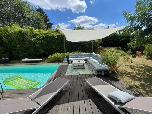 une cour arrière avec une piscine et une terrasse avec des chaises et un canapé dans l'établissement Villa du Lys, à Eysines