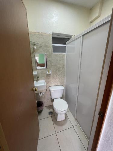 a small bathroom with a toilet and a shower at Hotel Oasis Cuyutlan in Cuyutlán