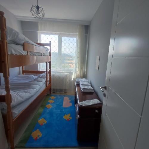 a small room with bunk beds and a blue rug at Akkayalar Aerie House in Çepni