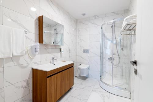a white bathroom with a sink and a shower at Sabırlar City Suites Hotel in Trabzon