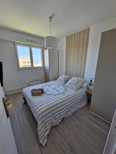 ein Schlafzimmer mit einem Bett mit einer gestreiften Decke und zwei Fenstern in der Unterkunft Villers vue sur mer in Villers-sur-Mer