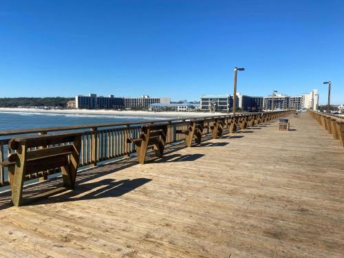 a wooden pier with benches on the beach at The Ellie Beach Resort Myrtle Beach, Tapestry By Hilton in Myrtle Beach