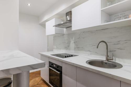 une cuisine blanche avec un évier et un comptoir dans l'établissement Cosy apartment - 1BR-4P - Near Nation, à Paris