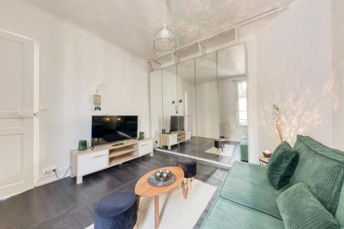 - un salon avec un canapé vert et une télévision dans l'établissement Charmant appartement Porte de Paris - Vincennes, à Vincennes