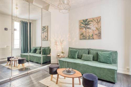 un salon avec un canapé vert et une table dans l'établissement Charmant appartement Porte de Paris - Vincennes, à Vincennes