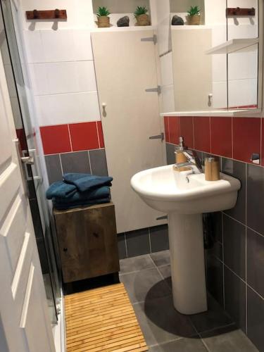 La salle de bains est pourvue d'un lavabo blanc et de carreaux rouges et blancs. dans l'établissement La Pierre De Lave appartement Le Corsaire, à Agde