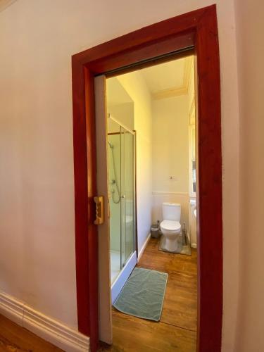 a bathroom with a toilet and a glass door at The Pink House in Faja Grande