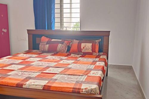 ティルパティにあるTiruchanoor Home stayのベッドルーム1室(オレンジ色の掛け布団と枕付きのベッド1台付)