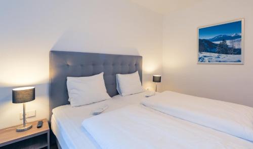 a bedroom with a large bed with white sheets at Residence Bellevue - incl Summercard in Zell am See