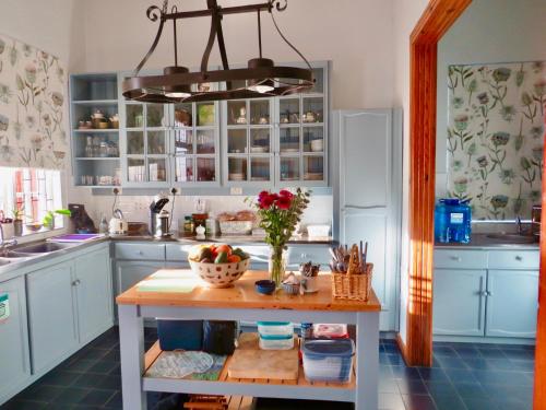 a kitchen with blue cabinets and a table with flowers on it at Whistlewood Guesthouse Walmer, Port Eizabeth in Port Elizabeth