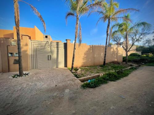 a house with a fence and palm trees at MARRAKECH , Ourika in Ourika