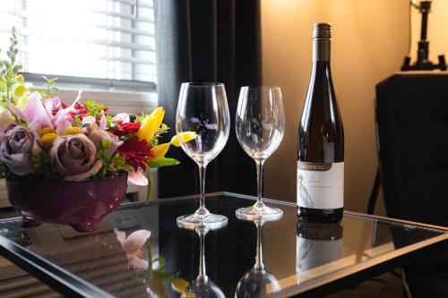 two wine glasses and a vase with flowers on a table at Jordan House Hotel in Jordan