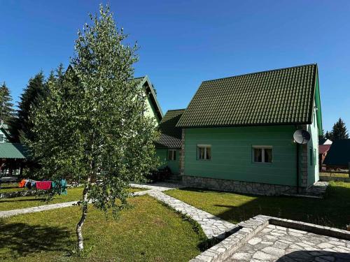 una casa verde con un árbol delante en Guest House Boka, en Žabljak