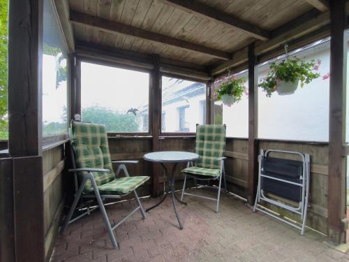 a screened in porch with chairs and a table at Andresen - Ferienwohnung mit Gartenlaube in Handewitt