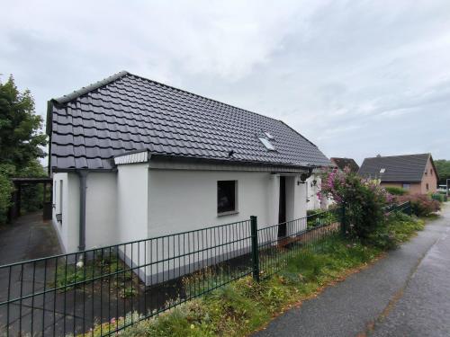 a white house with a black roof at Andresen - Ferienwohnung mit Gartenlaube in Handewitt