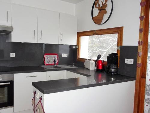 une cuisine avec des armoires blanches et un comptoir noir dans l'établissement Appartement 4 pièces pour 8 pers. avec garage, proche commerces et remontées mécaniques - FR-1-802-57, aux Gets