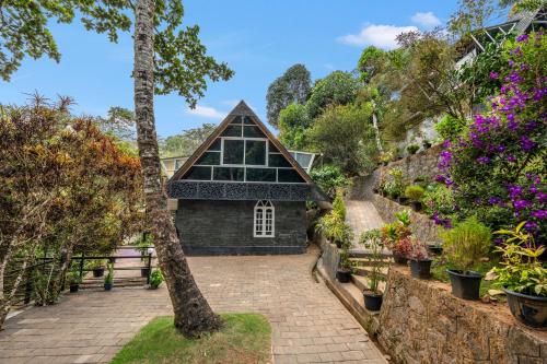 a garden with a black building and flowers at The Cove Lakkidi in Vythiri