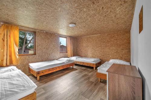 a room with two beds and a table and two windows at Chatová osada Bílý Kámen in Doksy