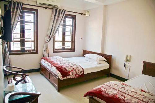 a bedroom with two beds and two windows at nhà nghỉ Quỳnh Vân in Lạng Sơn
