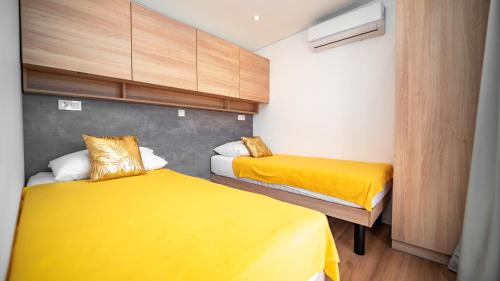 two beds in a small room with yellow sheets at House Red Earth - Kastel Stafilic in Kaštela