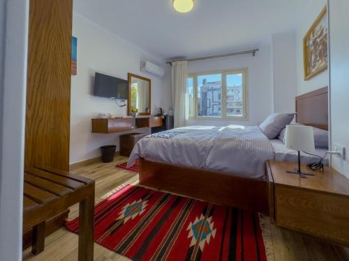 a bedroom with a bed and a desk and a window at Royal Crown Hotel Giza Pyramids View in Cairo