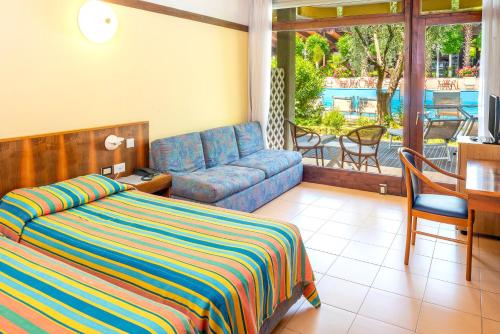 a bedroom with a bed and a couch and a table at Sporthotel Olimpo in Garda