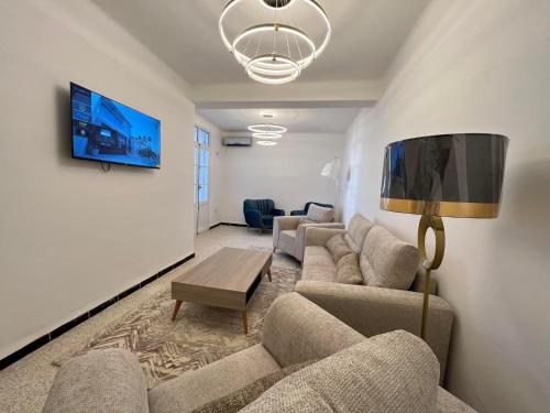 sala de estar con sofás y TV en la pared en Coast Haven, en Argel