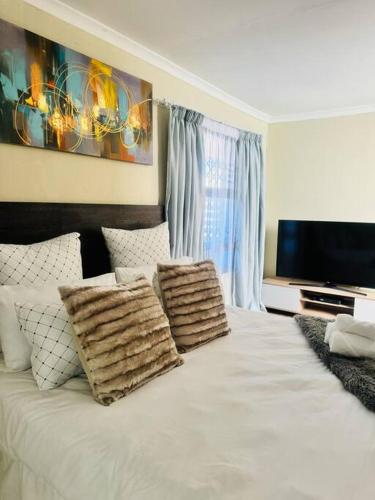 a bedroom with a white bed with pillows and a television at Private Studio in Cape Town, Near Canal Walk & Table Mountain in Cape Town