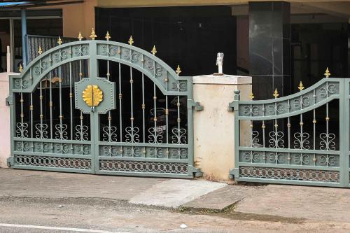 a green gate in front of a building at Hotel O Vel Vel Guest House in Palani