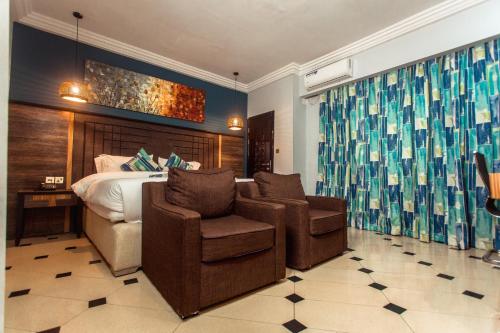a hotel room with a bed and two chairs at Marcsons Hotels and Resorts in Limbe