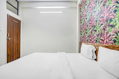 a bedroom with a white bed and a colorful wall at Collection O Verena in Indore