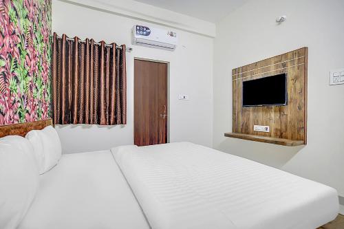 a white bedroom with a bed and a tv at Collection O Verena in Indore