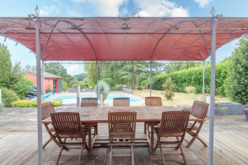 a wooden table and chairs under a red umbrella at Le Clos des Vignes in Loisy