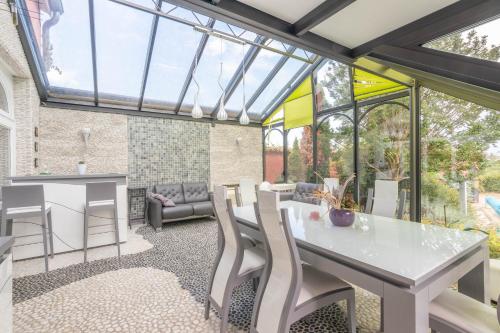 a conservatory with a white table and chairs at Le Clos des Vignes in Loisy