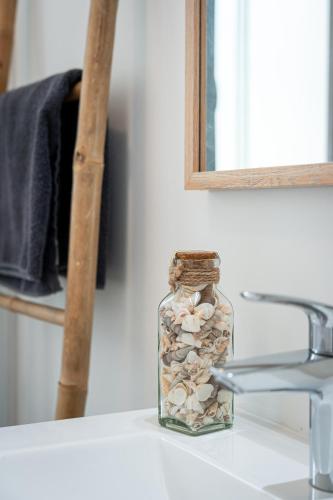 un bocal en verre rempli de coquillages posé sur un comptoir de salle de bain dans l'établissement Le Cool'Nest - Proche Disney et Val d'Europe 10mn, à Esbly