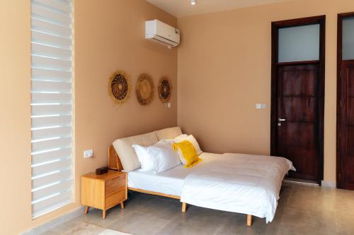 a bedroom with a bed with white sheets and yellow pillows at Tulia Luxury Villas in Mkunguni