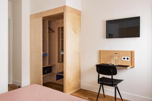 a room with a bed and a desk and a tv at New Hotel Op&eacute;ra in Paris