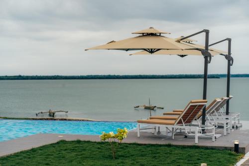 a table and chairs under an umbrella next to the water at Tulia Luxury Villas in Mkunguni