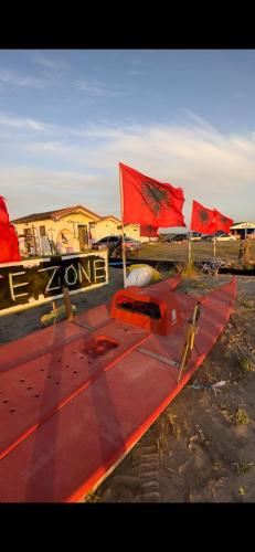 a red plane sitting in a field with red flags at White Houses Complex in Fier