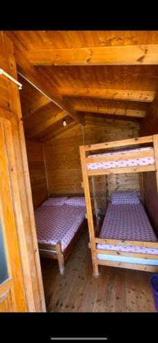 two bunk beds in a wooden cabin with purple sheets at White Houses Complex in Fier