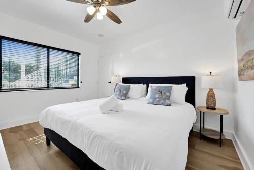 a white bedroom with a large bed with a ceiling fan at Waves On Walnut - Beach Access in Hollywood