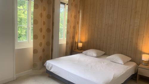 - une chambre avec un lit blanc et 2 fenêtres dans l'établissement L'Appart sur Jardin 42m2 très calme, à La Rochelle