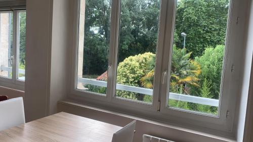 une salle à manger avec deux fenêtres et une table dans l'établissement L'Appart sur Jardin 42m2 très calme, à La Rochelle